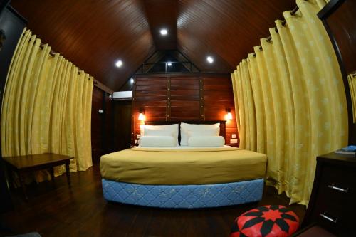 a bedroom with a large bed with yellow curtains at Nice Place Resort in Dambulla