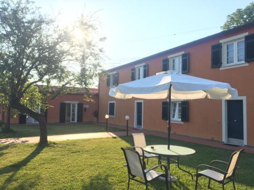 a table and chairs with an umbrella in front of a building at Casali Romei in Sarzana