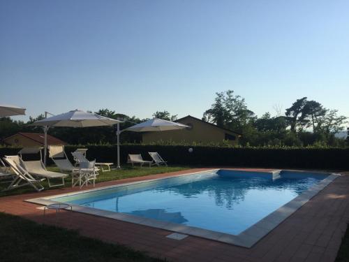 una piscina con sillas y sombrillas en un patio en Casali Romei, en Sarzana