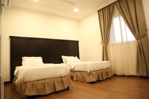 a bedroom with two beds with white sheets and a window at Sama Al Nakheel Furnished Apartments-Families only in Riyadh