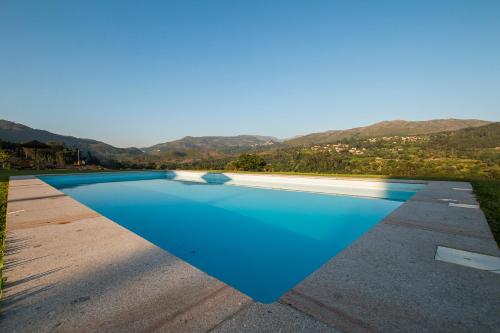 a blue swimming pool with mountains in the background at Casas de São Martinho in Arcos de Valdevez