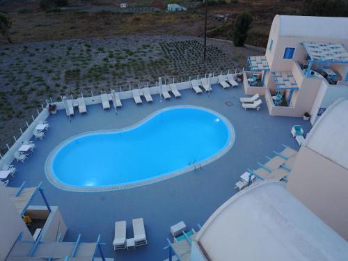 an overhead view of a swimming pool with chairs and tables at Unique Galini Oia - Adults Only in Oia