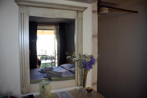 a mirror in a room with a bed and a vase of flowers at B&B Residenza Cardinale in Tropea