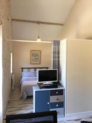 a bedroom with a bed and a desk with a television at Logis de L'Arceau in Celles
