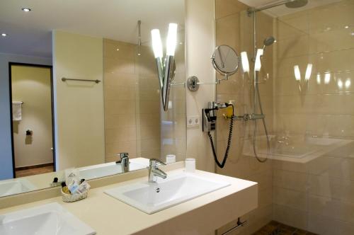 a bathroom with a sink and a shower and a mirror at Ringhotel Katharinen Hof in Unna