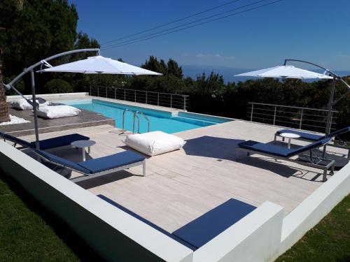 a swimming pool with two lounge chairs and umbrellas at Villa Anna Maria in Kriopigi
