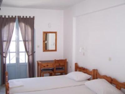 a bedroom with two beds and a table and a window at Panorama Hotel in Kalymnos