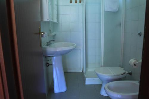 a white bathroom with a sink and a toilet at Ostello Su Mannau in Fluminimaggiore