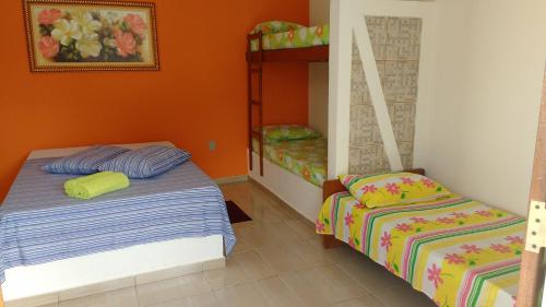 Duas camas num quarto com paredes cor de laranja em Pousada Sao Judas Tadeu em Guaratinguetá