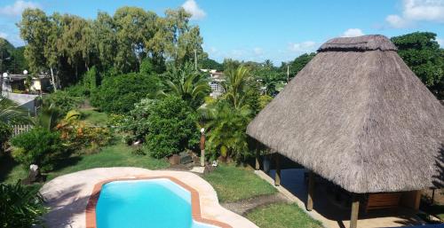 a resort with a swimming pool and a thatch roof at La Maison Soleil in Trou dʼ Eau Douce