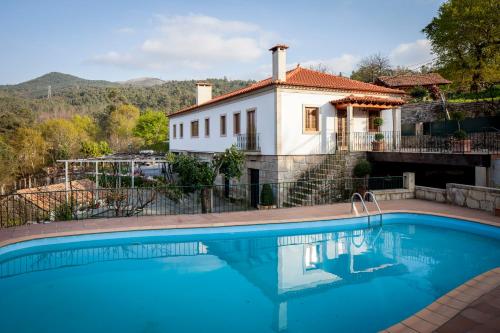 a villa with a swimming pool in front of a house at Cerca dos Passais in Entre Ambos os Rios