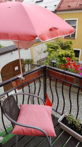a red umbrella and a chair on a balcony at Penzion-apartmán U Johana in Moravská Třebová