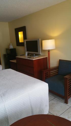 a hotel room with a bed and a tv and two chairs at Days Inn by Wyndham Cocoa Cruiseport West At I-95/524 in Cocoa
