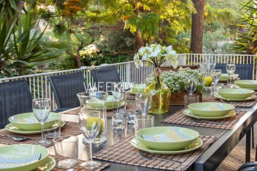 a table with green and white plates and glasses at Villa Sitges Tupinetti Beach at 1 min walk Amaizing Garden and View Center Sitges 5 minutes walk in Sitges
