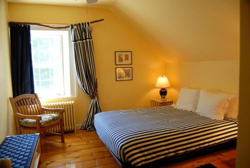 a bedroom with a bed and a window and a chair at Le Passe-Partout in Cowansville