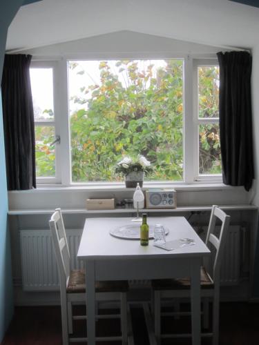 mesa y sillas en una habitación con 2 ventanas en B&B De Gouden Vlo en Donkerbroek