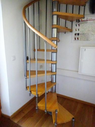 a wooden spiral staircase in a room with a wall at Les chaumières du Chêne in Pouillé