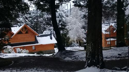 a cabin in the woods covered in snow at Melewe in Villa La Angostura