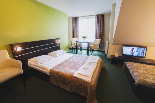 Pokój hotelowy z łóżkiem, stołem i telewizorem w obiekcie Biała Akacja Resort & Business w mieście Prudnik
