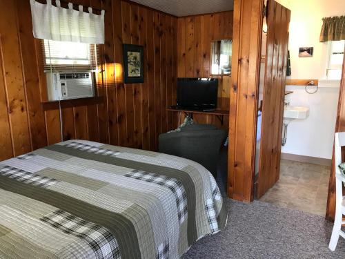 a bedroom with a bed and a television and a sink at Cedar Ridge Cabins in Honor