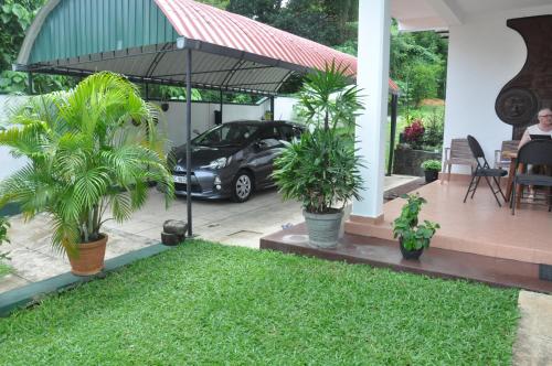 a house with a car parked under an umbrella at Samanala Garden Holiday Home in Hikkaduwa