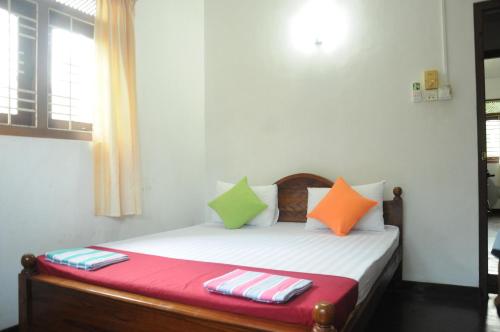 a bedroom with a bed with colorful pillows on it at Samanala Garden Holiday Home in Hikkaduwa