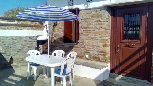a table and chairs with a blue and white umbrella at Monte Kechros in Arnados