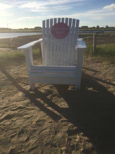 a white chair sitting in the sand on the beach at Gästehaus Margareth in Büsum