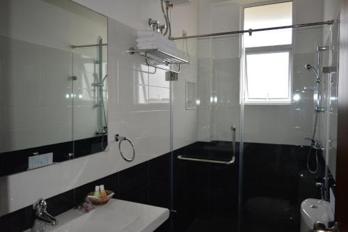 a bathroom with a shower and a sink and a mirror at Tranquil Villa in Nuwara Eliya
