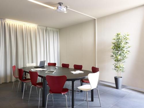 a conference room with a black table and red chairs at Casalgrande Hotel in Salvaterra