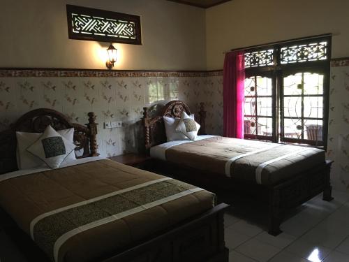 a bedroom with two beds and a window at Eka's Homestay in Ubud