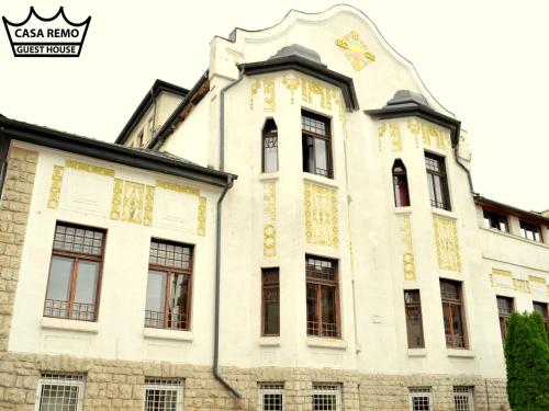 a white building with a clock on the top of it at Casa Remo - Guesthouse in Turda