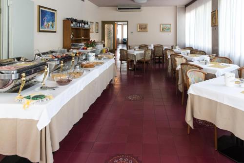 a dining room with tables with white tablecloths at Hotel Gloria in Salsomaggiore Terme