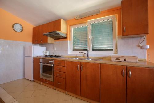 a kitchen with wooden cabinets and a sink and a window at Apartment and rooms Roko in Zaglav