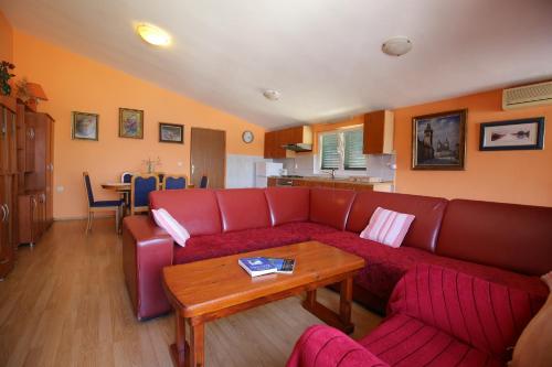 a living room with a red couch and a table at Apartment and rooms Roko in Zaglav