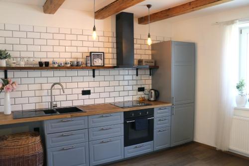 a kitchen with gray cabinets and a sink and a refrigerator at Onefourfour Apartment in Brandýs nad Labem-Stará Boleslav