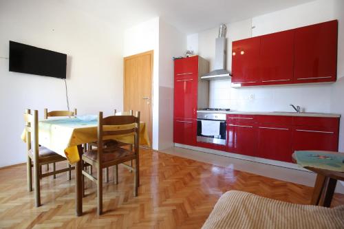a kitchen with red cabinets and a table with chairs at Apartment and rooms Roko in Zaglav
