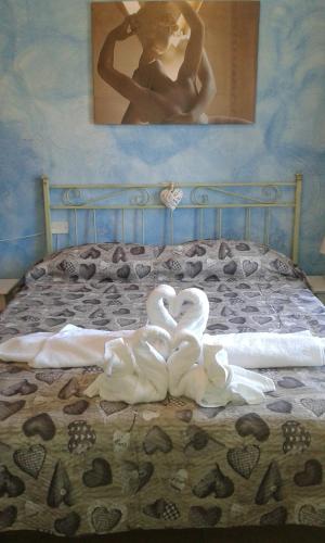 Dois cisnes brancos estão sentados numa cama. em Appartamento Shabby em Bosa