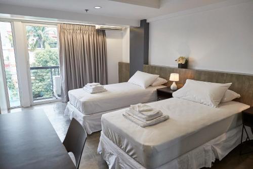 a hotel room with two beds and a window at 5880 Enriquez Residences in Manila