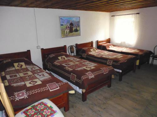 a room with three beds and a table and a window at Kulla e Sadri Lukes in Theth