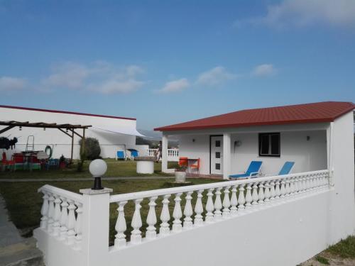 a white house with a white fence and blue chairs at Bed & Breakfast Vista in Alcobaça