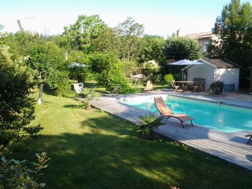 a backyard with a swimming pool and a wooden deck at Chambres d'Hôtes Les Douves in Saint-Thomas