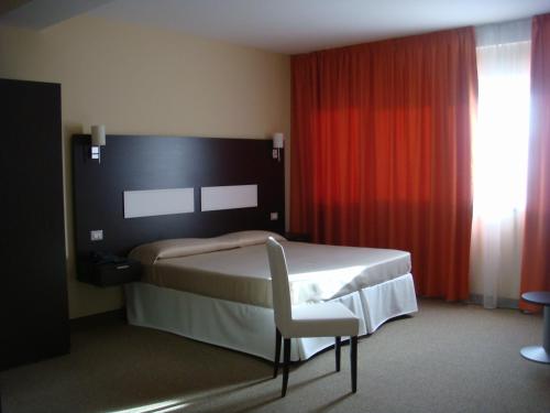 a bedroom with a bed and a chair and a window at Santa Loja Hotel Residence in Tito
