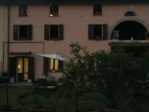 a building with a table and an umbrella in front of it at B&B Happiness in the Country in Brescello