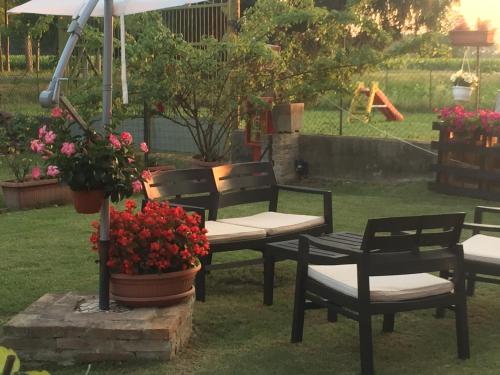 a group of chairs and an umbrella and flowers at B&B Happiness in the Country in Brescello