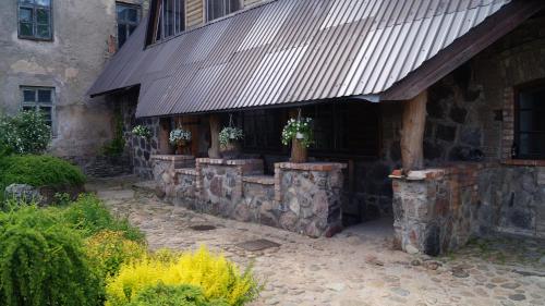 a stone building with potted plants on top of it at Guest house Jumiezis in Pļaviņas
