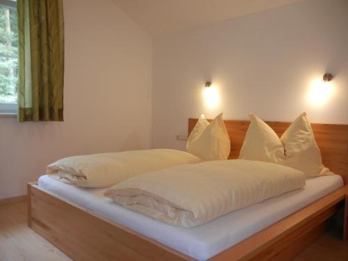 Schlafzimmer mit einem Bett mit weißer Bettwäsche und Kissen in der Unterkunft Haus Terra in Ramsau am Dachstein