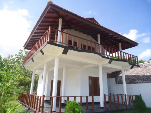 a house with a balcony on top of it at Pearl Cave Cabanas & Resturant in Tangalle