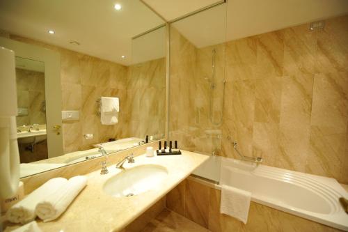 a bathroom with a sink and a tub and a mirror at Hotel Acquaviva Del Garda in Desenzano del Garda