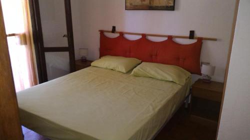 a bedroom with a large bed with a red headboard at Splendida Villetta vicino al mare in Villasimius